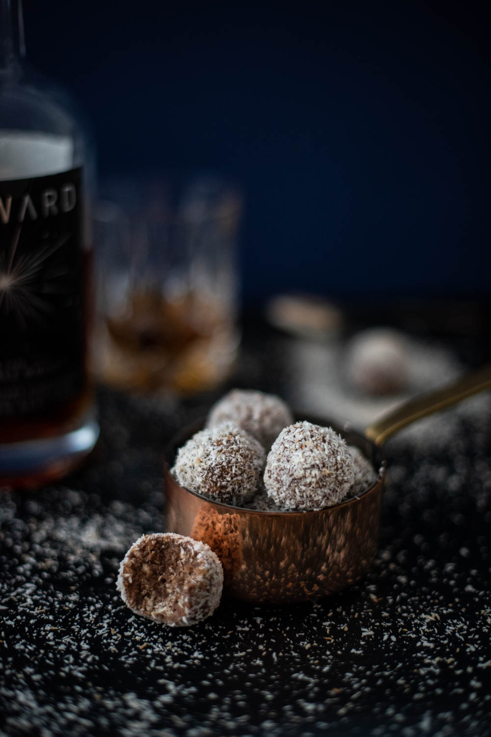 Close of of chocolate whisky balls with a glass of whisky in the background